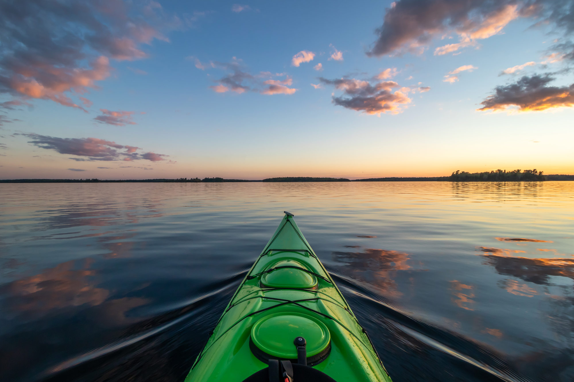 Green kayak on a lake at sunset